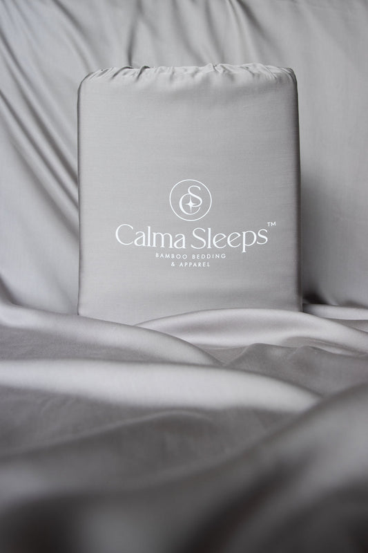 Grey Calma Sleeps pack of sheet set sitting on top of grey bamboo bedsheets
